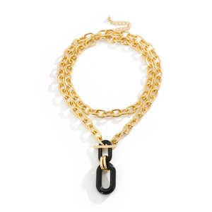 Detail of layered gold metal chain necklace with T-bar closure and black oval pendant