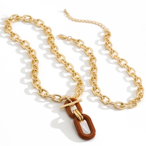 Detail of layered gold chain necklace featuring brown resin links and T-bar toggle design