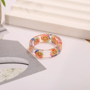 Detalle de anillo de resina transparente con flores sonrientes de colores vivos