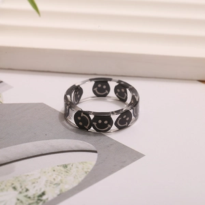 Detalle macro de un anillo de resina transparente con un diseño de cara sonriente negra