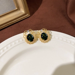 Detail von Vintage-Smaragd-Ohrringen mit Goldfiligran und Perlen auf Samthintergrund