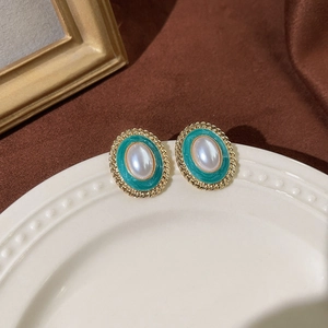 Detailansicht der Retro-Emaille-Ohrstecker in Smaragdgrün mit Perle auf Keramikteller