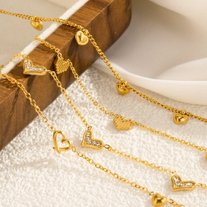 Detail van gelaagde gouden titanium stalen harthangers met matte en zirkoon texturen
