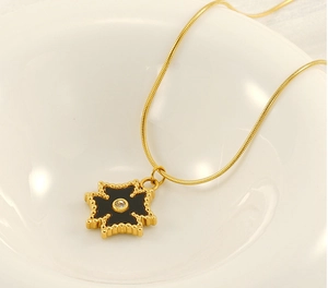 Détail macro du pendentif étoile polaire dorée avec zircon placé dans un bol blanc