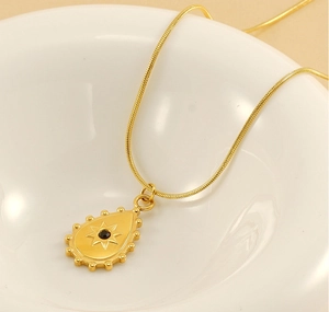 Détail du pendentif goutte doré avec étoile gravée et pierre noire sur chaîne serpent