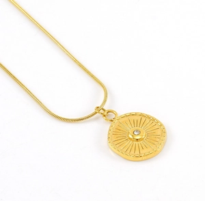 Gros plan détaillé d'un pendentif soleil doré sur une chaîne maille serpent lisse