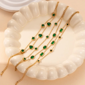 Detail of gold chain bracelets featuring green star, heart, and oval zircon stones