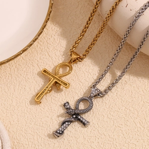 Macro detail of gold and silver Ankh snake pendants with sparkling crystals on wheat chains