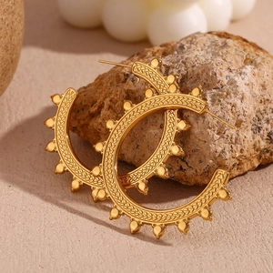Macro detail of gold-plated hoop earrings with wheat ear texture and beaded edge