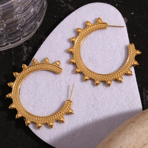 Macro detail of gold 18K plated hoop earrings with bohemian wheat pattern texture