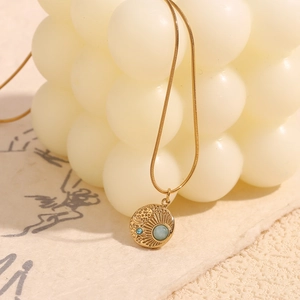 Macro view of 18K gold-plated star compass pendant with green gem and blue rhinestone