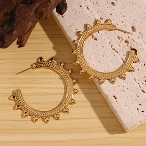 Detailed view of gold hoop earrings with bohemian wheat grain texture on stone base