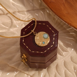 Detailed relief of sun and moon on 18K gold-plated compass pendant with blue gemstone