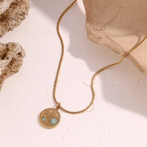 Detail of 18K gold plated compass pendant with star patterns and inlaid gemstones
