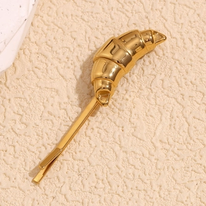 Detail view of a 18K gold plated stainless steel croissant hair clip on a cream background