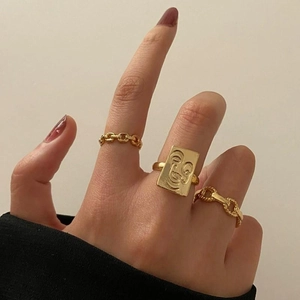 Three-piece gold ring set featuring abstract face relief and stylish chain link bands