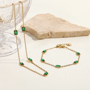 Detail of gold chain necklace and bracelet set with emerald green rectangular stones