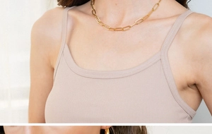 Vue macro d'un collier chaîne trombone en acier inoxydable plaqué or 18K sur un modèle