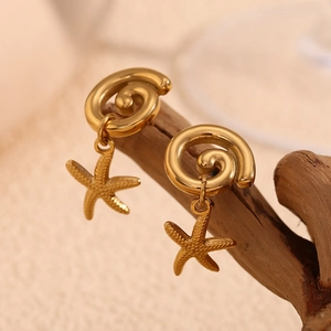 Detailed close-up of 18K gold plated starfish earrings hanging on a rustic wooden stand