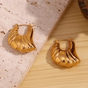 Detailed view of hollow wing earrings in 18K gold plated stainless steel on stone