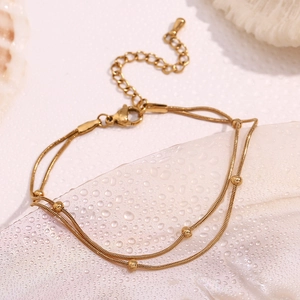Macro view of gold-plated double-layer snake chain with beads on a frosted background