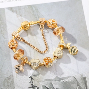 Gold-plated bee charm bracelet with amber glass beads and heart charms on a snake chain