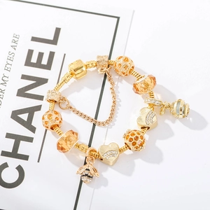 Detailed close-up of a gold-plated bee charm bracelet with heart beads and safety chain