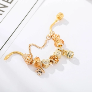Detail of gold-plated bracelet featuring bee charms, amber crystal, and honeycomb beads