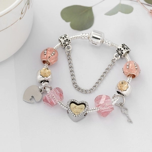 Rosa DIY Charm-Armband mit Herzschloss und Schlüssel-Anhänger auf silberner Schlangenkette
