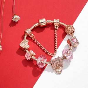 Bracelet serpent or rose avec perles en cristal rose et breloques cœur sur fond bicolore