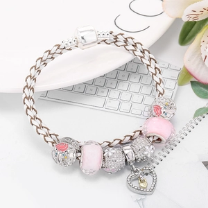 White leather charm bracelet with pink glass beads and heart pendant on white ceramic plate