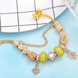 Goldenes Herz-Charm-Armband mit gelben Kristallen und floralen Anhängern auf Schlangenkette