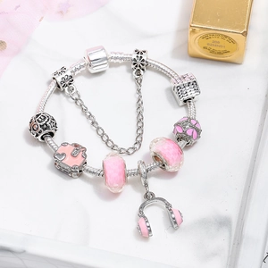 Elegant silver snake chain bracelet with pink charms, travel bag and headphone pendants