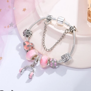 Pink charm bracelet with handbag and headphones pendants on a silver snake chain