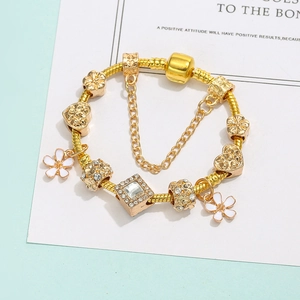Elegante gouden slangarmband met witte emaille bloemen en bedeltjes van kristal