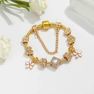 Elegante gouden slangenarmband met kristallen bedeltjes en witte emaille bloem