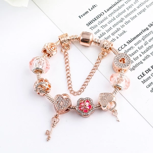 Roségoldenes Schlangenarmband mit Herzschloss und rosa Kristallblumen-Anhängern