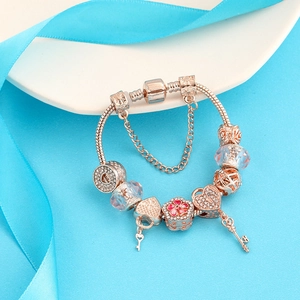 Roségoldenes Charm-Armband mit Herzschloss und Blumenperlen auf blauem Hintergrund
