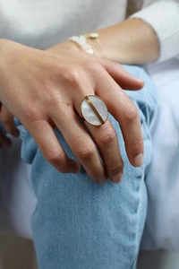 Close-up van een minimalistische gouden ring met parelmoer inleg aan een vinger