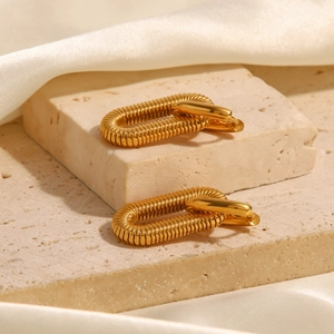 Detail of 18K gold plated stainless steel chain earrings on stone and silk background