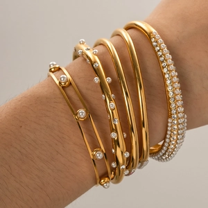 Detailed shot of layered 18K gold-plated bangles with pearls and crystals on wrist