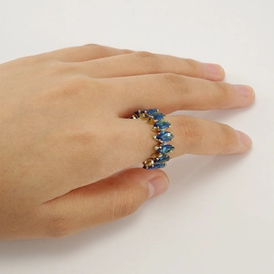 Detailed view of 18K gold ring featuring marquise-cut blue gemstones on finger