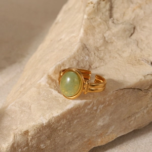 Detail of adjustable gold ring featuring a green stone set against a textured stone base