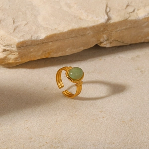 Macro detail of an 18K gold stainless steel ring with a round green zircon stone