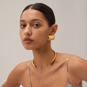 Primo piano della collana girocollo in oro 18 carati e dell'orecchino geometrico su modella