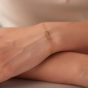 Dettaglio di un elegante bracciale in titanio placcato oro 18K con cinque zirconi incastonati