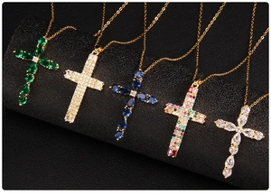 Close-up of gold cross pendants featuring colorful zircon and sapphire stones on stands