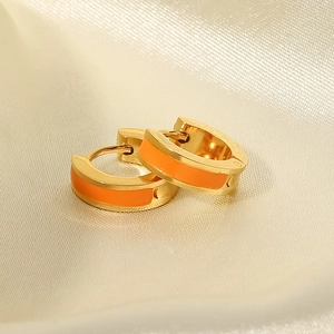 Détail de créoles plaquées or 18K avec émail orange vif sur fond en soie de luxe