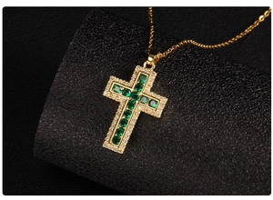 Macro detail of gold cross pendant with emerald green zircons on black display stand