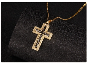 Macro shot of gold cross pendant with black gemstone inlay and pavé zircon edges